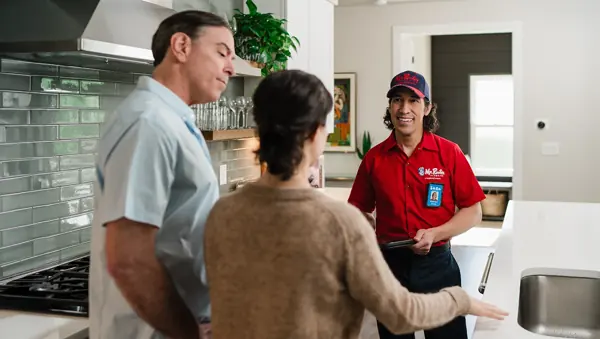 Mr. Rooter technician discussing plumbing service with homeowners